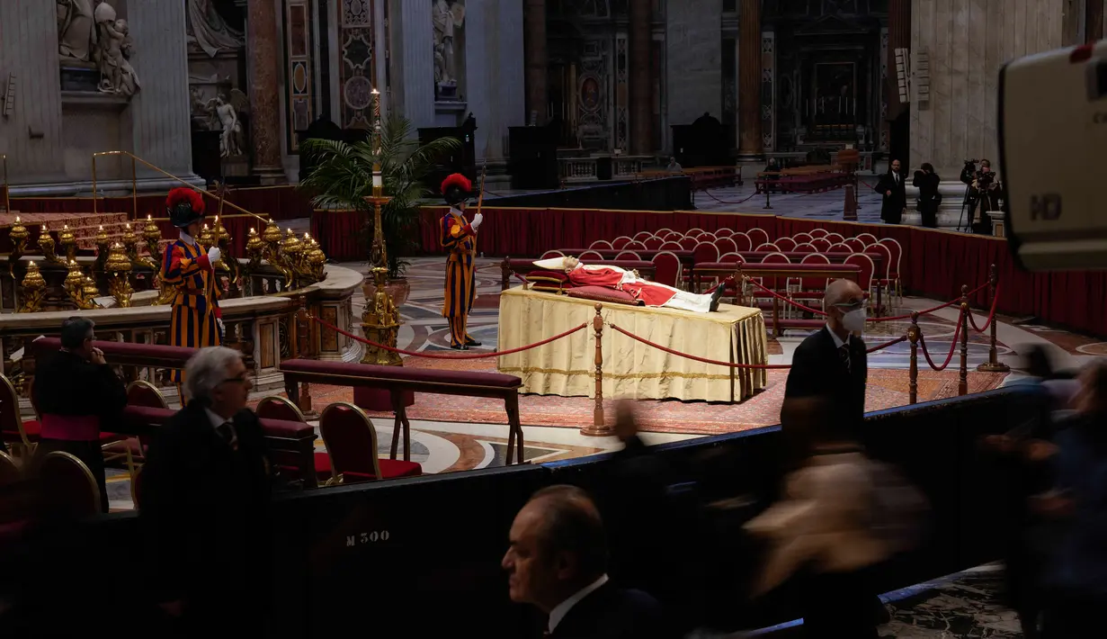 Orang-orang melihat jenazah mendiang Paus Emeritus Benediktus XVI yang disemayamkan di Basilika Santo Petrus, Vatikan, Senin (2/1/2023). Benediktus XVI, teolog Jerman yang akan dikenang sebagai paus pertama dalam 600 tahun yang mengundurkan diri, telah meninggal pada 31 Desember 2022 di usia 95 tahun. (AP Photo/Andrew Medichini)