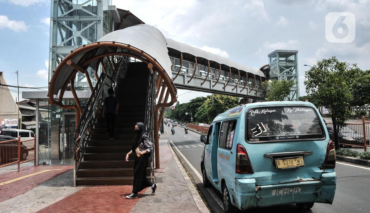 Sebuah angkutan umum berhenti di bawah jembatan penyeberangan orang (JPO) di Jalan Kolonel Sugiono, Duren Sawit, Jakarta, Senin (7/2/2022). Tak hanya menonjolkan keindahan arsitekturnya, JPO ini juga ramah bagi penyandang disabilitas karena sudah dilengkapi dengan lift. (merdeka.com/Iqbal S Nugroho)