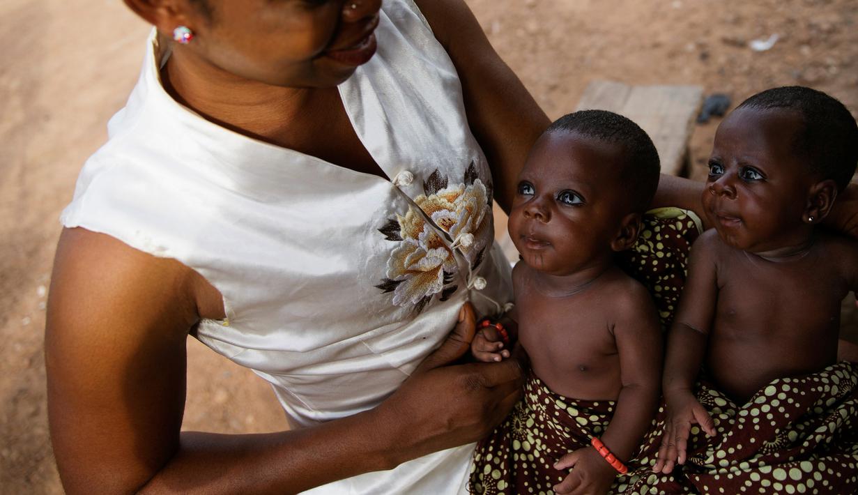 Suliat Ogunjimi menggendong bayi kembar tidak identik, Afusat Ganiyu dan Ganiyatu Adesope di Igbo Ora, Negara Bagian Oyo, Nigeria pada 3 April 2019. Saking banyaknya anak kembar yang dilahirkan, Igbo Ora dijuluki sebagai "ibu kota kembar dunia". (REUTERS/Afolabi Sotunde)