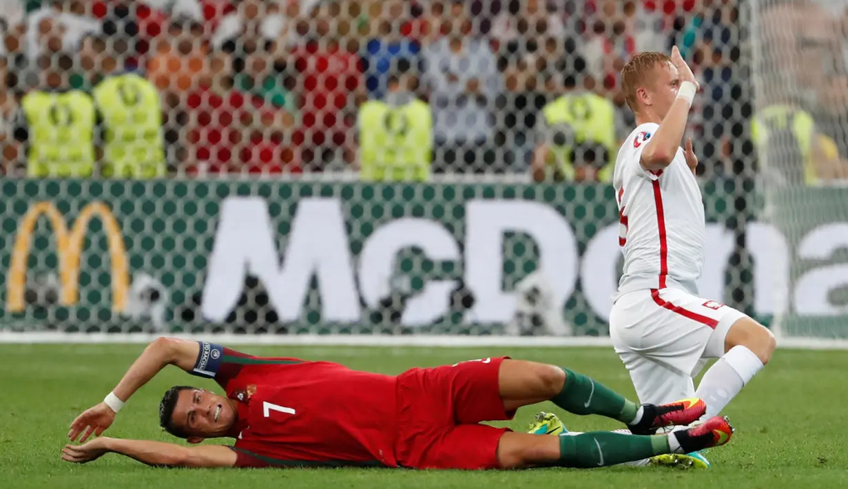 Striker Portugal, Cristiano Ronaldo, dilanggar pemain Polandia, Kamil Glik, pada laga perempat final Piala Eropa 2016 di Stade Velodrome, Marseille, Jumat (1/7/2016) dini hari WIB. (Reuters/Yves Herman)