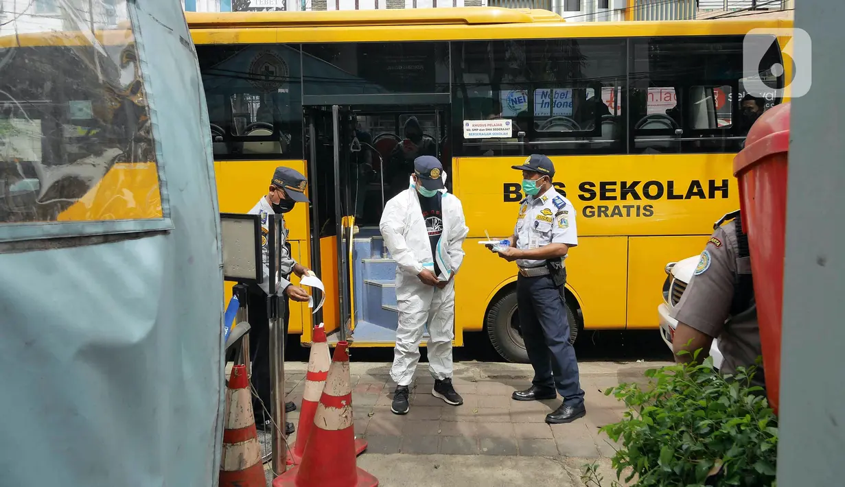 Petugas mengenakan APD saat akan mengantarkan pasien COVID-19 menuju RSDC Wisma Atlet di Puskesmas Kecamatan Tebet, Jakarta, Kamis (3/2/2022). Satgas Penanganan COVID-19 mencatat kenaikan kasus positif COVID-19 dalam satu pekan terakhir. (Liputan6.com/Herman Zakharia)