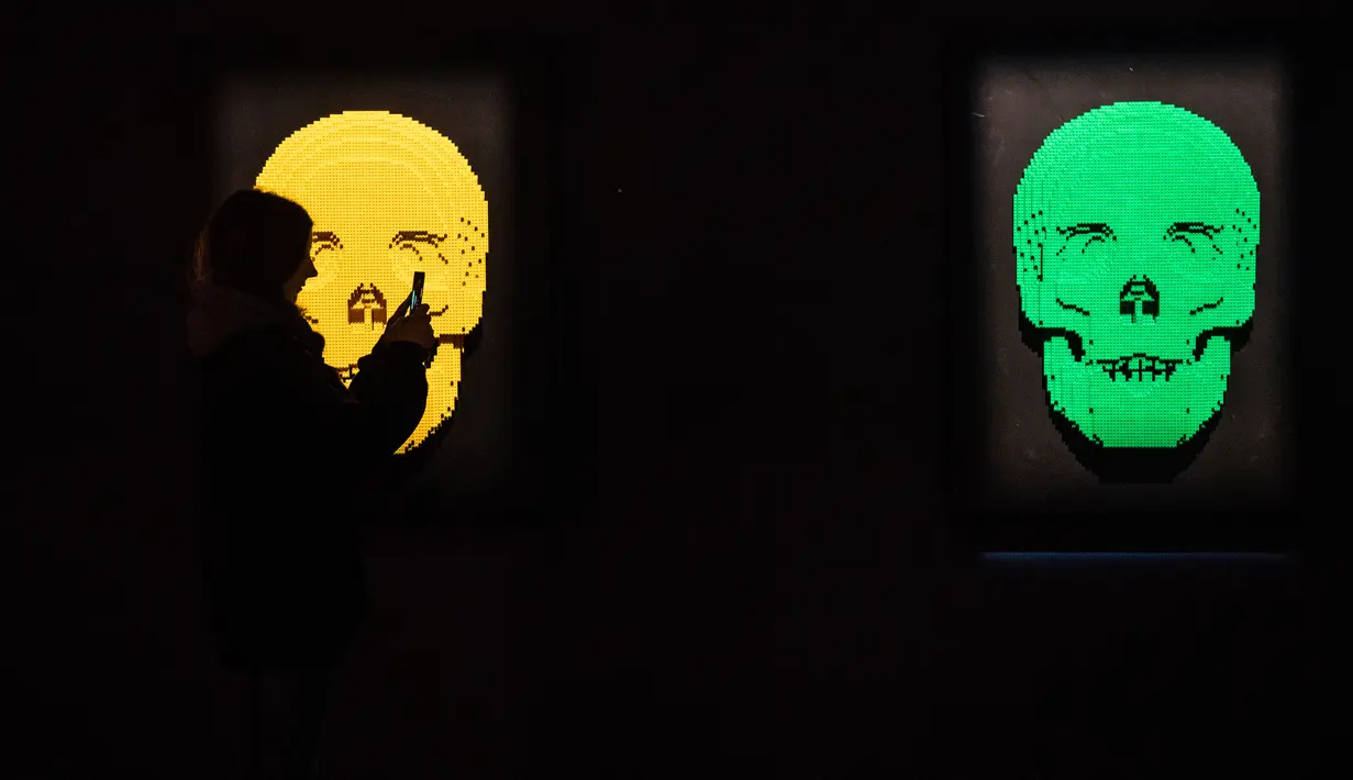 Seseorang mengambil gambar patung "Skulls" yang terbuat dari susunan balok lego pada pameran Art of the Brick di Turin, Italia, Kamis (15/11). Pameran tersebut menampilkan berbagai patung lego karya seniman AS, Nathan Sawaya. (MARCO BERTORELLO/AFP)