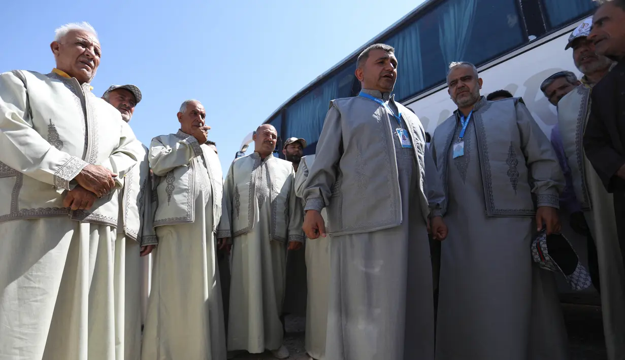 Warga Suriah dari provinsi Idlib, berkumpul sebelum menaiki bus ke Tanah Suci Makkah di kota Binnish, Senin (22/7/2019). Jemaah calon haji asal Suriah melakukan perjalanan ke Arab Saudi untuk menjalankan ibadah haji dari perbatasan Bab al-Hawa yang berseberangan dengan Turki. (Omar HAJ KADOUR/AFP)