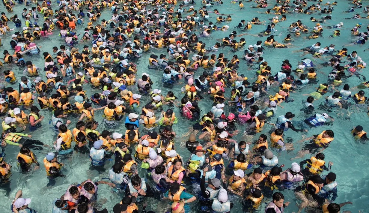 Wisatawan memadati water park yang dikenal dengan Caribbean Bay di Yongin, luar Seoul, Senin (6/8). Gelombang panas yang melanda Korea Selatan akhir-akhir ini membuat ratusan warga memenuhi kolam renang untuk mengurangi hawa panas. (Ed JONES/AFP)