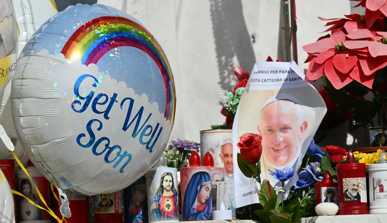 Balon-balon dipasang di patung Yohanes Paulus II di mana orang-orang datang untuk berdoa di luar rumah sakit Gemelli tempat Paus Fransiskus dirawat karena pneumonia, di Roma pada 23 Februari 2025. (Alberto PIZZOLI/AFP)