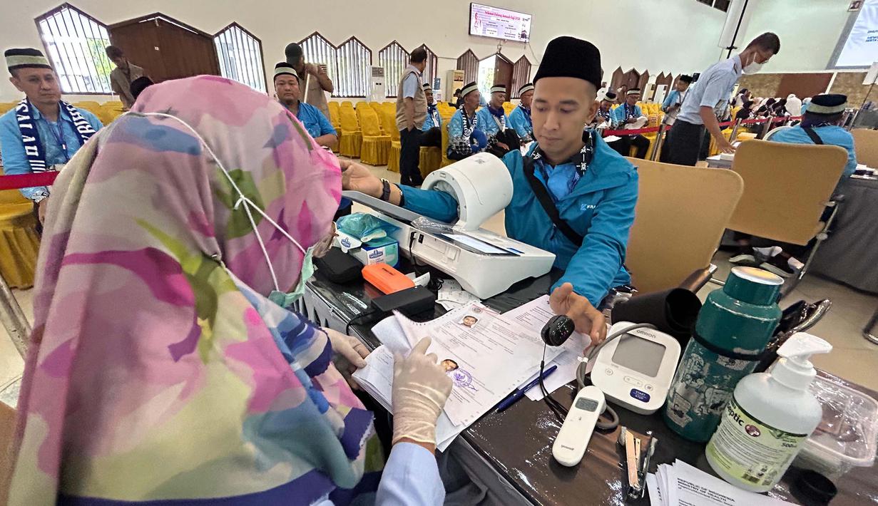 Setibanya di lokasi, para jemaah langsung menjalani proses pemeriksaan kesehatan, penyelesaian administrasi, serta penguatan manasik haji dan sosialisasi kesehatan. Tampak dalam foto, petugas memeriksa kesehatan calon haji setibanya di Asrama Haji Pondok Gede, Jakarta, Selasa (21/4/2026). (merdeka.com/Arie Basuki)