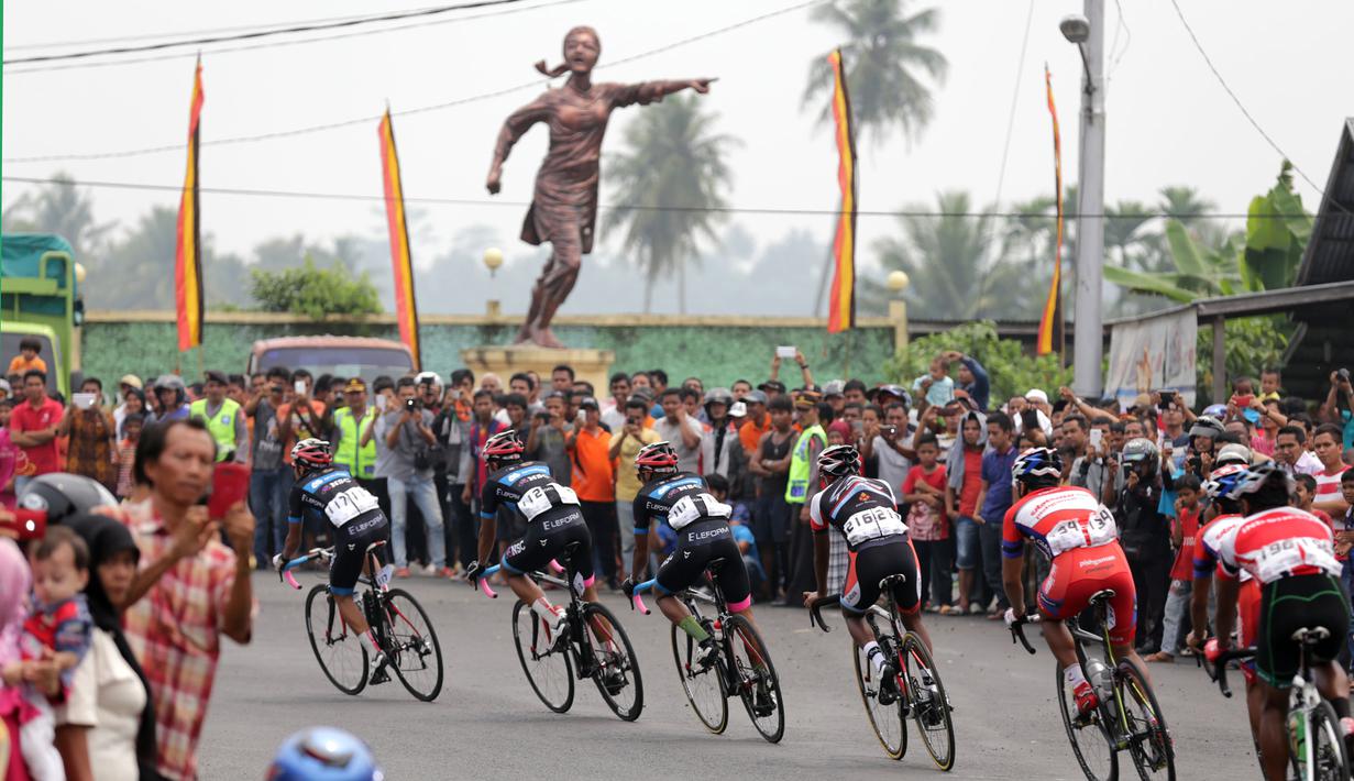 Para pebalap saat melewati Tugu Siti Manggopoh, Simpang Gudang, Kabupaten Agam di Etape 8 Tour de Singkarak 2015 Pasaman Barat-Lawang Park, Kabupaten Agam, Sabtu (10/10/2015). (Bola.com/Arief Bagus)