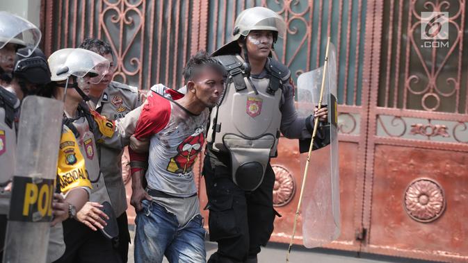 Polisi menangkap seorang pria saat tarjadi bentrok dengan massa di kawasan Petamburan, Jakarta Barat, Rabu (22/5/2019). Kapolres Metro Jakarta Barat Kombes Hengki Haryadi menduga kuat massa aksi yang diamankan bukan merupakan warga Jakarta. (Liputan6.com/Faizal Fanani)