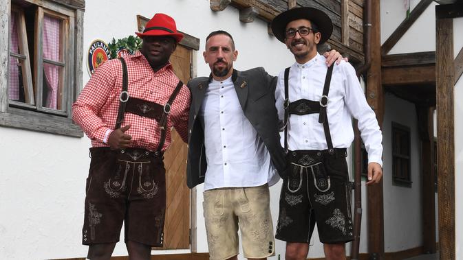 Pemain Bayern Munchen Franck Ribery (tengah) mengenakan gaun tradisional Bavaria, Lederhosen, saat berpose dengan dua orang teman setibanya pada festival bir tahunan Oktoberfest di Munich, Jerman, Minggu (7/10). (Christof STACHE / AFP)