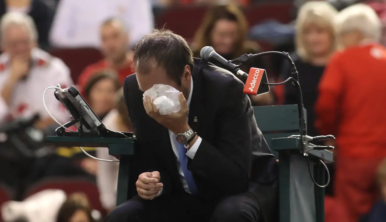 Wasit asal Prancis, Arnaud Gabas, mengompres bagian wajahnya yang terkena bola tenis saat petenis Kanada Denis Shapovalov melawan petenis Inggris Kyle Edmund pada putaran pertama Piala Davis di Ottawa, Kanada, Minggu (5/2). (Lars Hagberg/AFP)