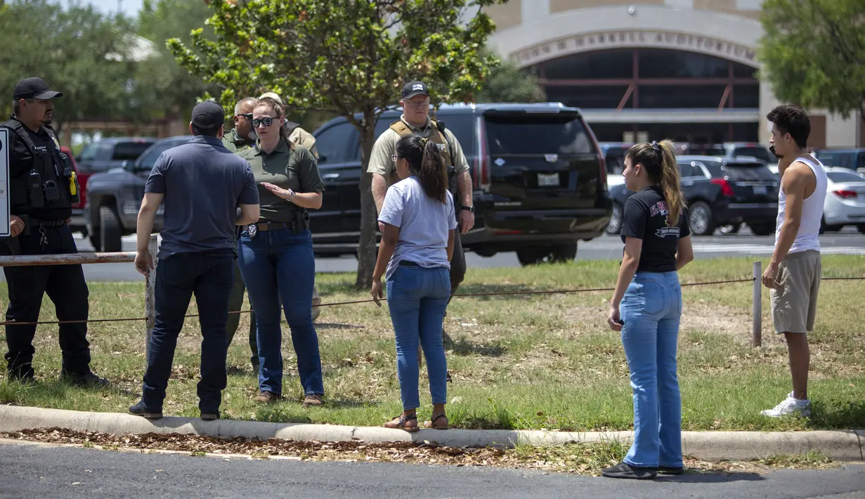 Seorang aparat penegak hukum berbicara dengan orang-orang di luar Uvalde High School setelah penembakan dilaporkan pada hari sebelumnya di Robb Elementary School, Uvalde, Texas, Amerika Serikat, 24 Mei 2022. Pelaku yang memakai senjata rifle diduga ditewaskan oleh aparat, namun investigasi lebih lanjut masih diperlukan. (William Luther/The San Antonio Express-News via AP)