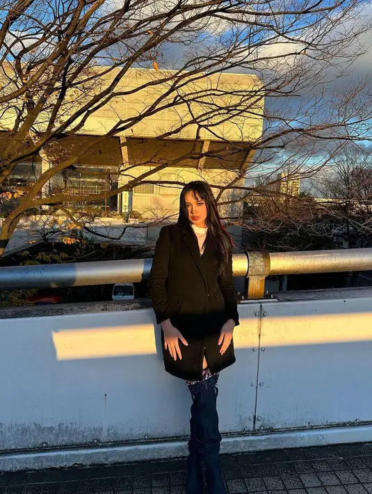 Lyodra Ginting mengenakan coatdress hitam yang dipadukan dengan high boots [instagram/lyodraofficial]