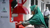 Seorang Warga mencoba alat cuci tangan sensorik otomatis yang disumbangkan Telkom University di Masjid dan Madrasah di Bojongkunci, Kabuapten Bandung. (Dok: Telkom University)