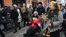 Seringkali 'Didukh' berfungsi sebagai pengganti pohon Natal dan menjadi pusat perayaan. Tampak dalam foto, para veteran Ukraina yang terluka memegang hiasan tradisional 'Didukh' saat mereka mengikuti prosesi Malam Natal di Lviv pada 24 Desember 2025. (YURIY DYACHYSHYN/AFP)