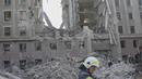 Petugas pemadam kebakaran membersihkan puing-puing gedung pemerintah yang terkena roket Rusia di Mykolaiv (29/3/2022). Serangan Rusia menghancurkan gedung pemerintah daerah di kota Mykolaiv, Ukraina selatan, pelabuhan utama yang diserang selama berminggu-minggu. (AFP/Bulent Kilic)