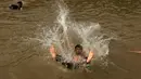 Seorang pria melompat ke sungai untuk mendinginkan tubuhnya saat cuaca panas yang ekstrem di Islamabad, Pakistan, (23/6/2015). Gelombang panas membuat warga Pakistan tak bisa jauh dari air untuk bertahan hidup. (REUTERS/Faisal Mahmood)