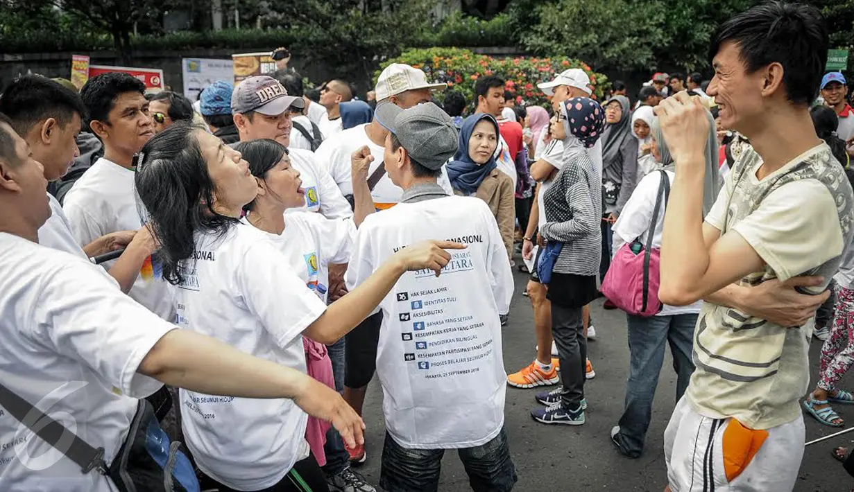 Sejumlah penyandang disabilitas tuna rungu dan tuna wicara memperagakan bahasa isyarat kepada warga dalam rangka memperingati Hari Tuli Internasional di arena Car Free Day, Jakarta, Minggu (25/9). (Liputan6.com/Faizal Fanani)