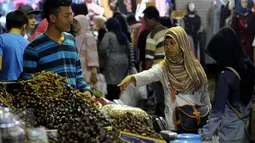 Pedagang melayani pembeli buah kurma di salah satu kios pasar Tanah Abang, Jakarta, Jumat (10/6). Menurut pedagang, penjualan kurma di bulan Ramadan mengalami peningkatan hingga dua kali lipat dibandingkan hari biasanya. (Liputan6.com/Johan Tallo)