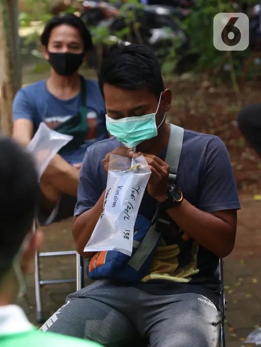 Warga meniupkan kantong saat menjalani tes deteksi COVID-19 dengan metode GeNose C19 usai terjaring razia penggunaan masker di Kelurahan Sudimara Barat, Kota Tangerang, Kamis (27/5/2021). Tes tersebut untuk menekan penyebaran corona di wilayah tersebut. (Liputan6.com/Angga Yuniar)