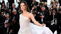 Model Alessandra Ambrosio berpose saat tiba menghadiri pemutaran film "The Dead Don't Die" selama Festival Film Cannes ke-72 di Prancis (14/5/2019). Model cantik asal Brasil ini tampil memesona dengan gaun putih sutra transparan Ralph & Russo. (AFP Photo/Christophe Simon)