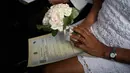 Mempelai wanita memegang buket bunga selama pernikahan drive-thru di kantor pencatatan sipil di Santa Cruz, Rio de Janeiro, Brasil, 28 Mei 2020. Fasilitas ini untuk memudahkan dan membantu pasangan yang ingin mengesahkan hubungan saat pandemi covid-19. (AP/Silvia Izquierdo)
