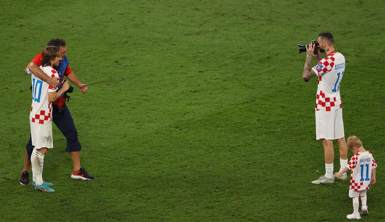 Pemain Kroasia, Marcelo Brozovic (kanan) bertukar peran dengan fotografer tim yang ingin foto bersama Luka Modric. (AFP/Adrian Dennis)