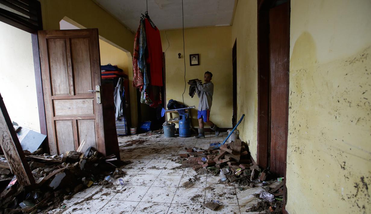 Warga lokal Alimin membersihkan puing-puing dari rumahnya setelah tsunami di Carita, Banten, Kamis, (27/12). Pemerintah telah memperluas zona larangan di sekitar pulau gunung berapi pulau yang memicu tsunami. (AP Photo/Achmad Ibrahim)