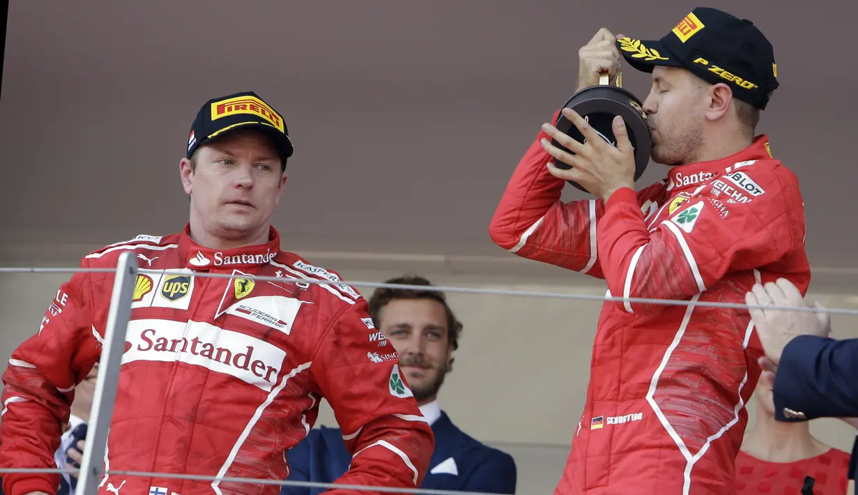 Pebalap Ferrari, Sebastian Vettel merayakan kemenangan sementara Kimi Raikkonen hanya melihatnya dengan tatapan kosong pada F1 GP Monako, (28/5/2017). (AP/Claude Paris)