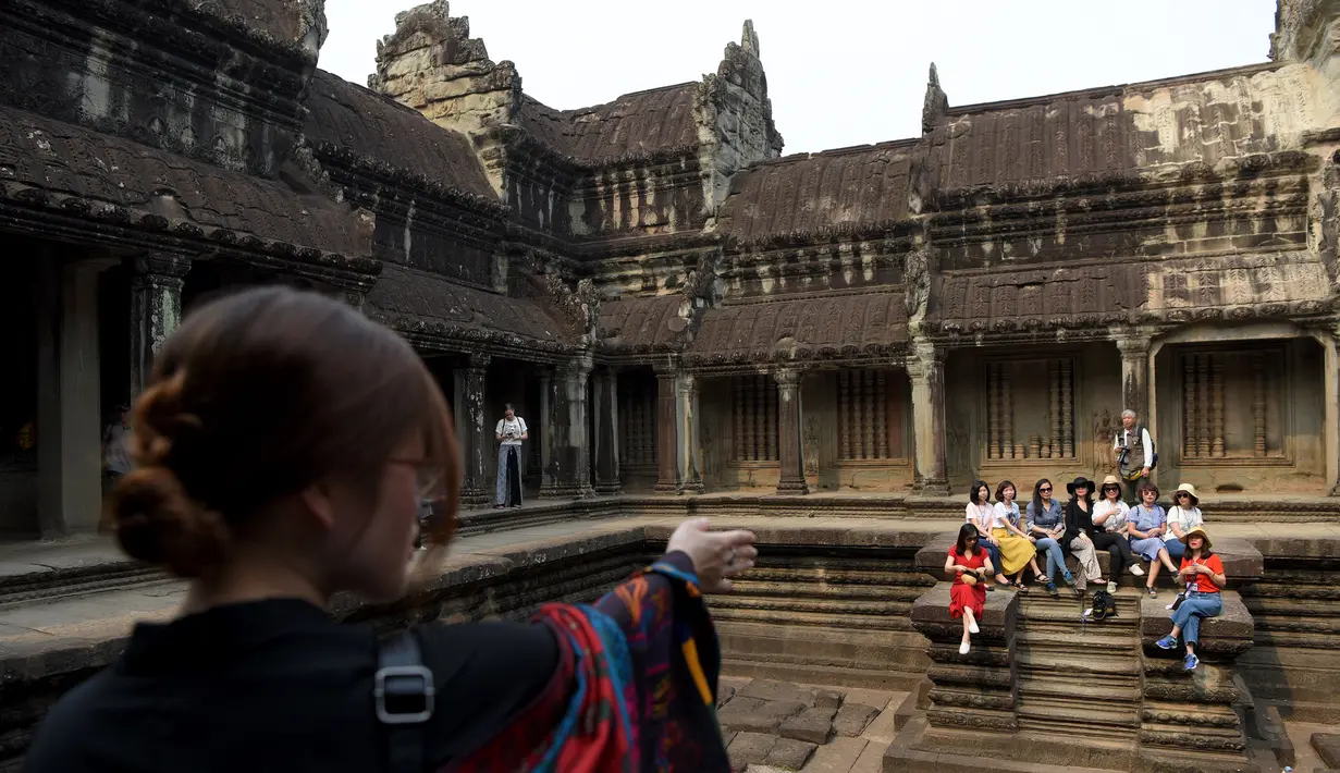 Turis bersiap untuk berfoto saat mengunjungi candi Angkor Wat di provinsi Siem Reap, Kamboja pada 16 Maret 2019. Pada akhir abad 12, Candi Hindu terbesar dunia ini dialihfungsikan sebagai kuil umat Buddha. (TANG CHHIN Sothy / AFP)