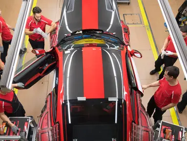 Pekerja memasang pintu mobil sport Porsche GT2RS di pabrik Porsche di Stuttgart, Jerman (26/1). Perusahaan Porsche membagikan bonus besar kepada karyawannya karena hasil penjualan mereka mencapai rekor tertinggi tahun lalu. (AFP Photo/Thomas Kienzle)