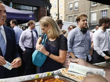 Gubernur Bank Inggris, Carney singgah untuk membeli makan siang di Whitecross Street Market di London, Selasa (13/9). Carney menunjukkan kepada penjual tentang kelebihan uang keluaran baru Bank Inggris. (REUTERS / Stefan Wermuth)