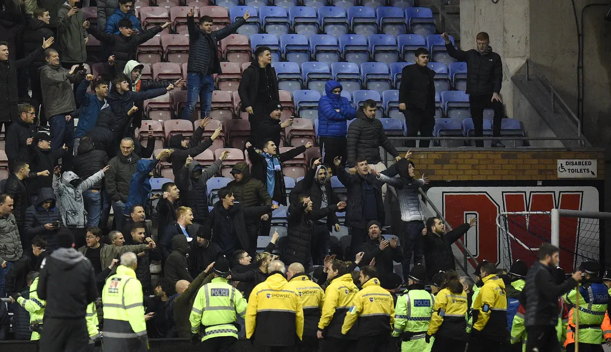 Pendukung Manchester City bereaksi setelah tim kesayangnya dikalahkan Wigan Athletic pada babak kelima Piala FA di Stadion DW, Senin (19/2). Suporter Manchester City melemparkan berbagai benda, termasuk papan iklan, ke arah lapangan. (Oli SCARFF/AFP)