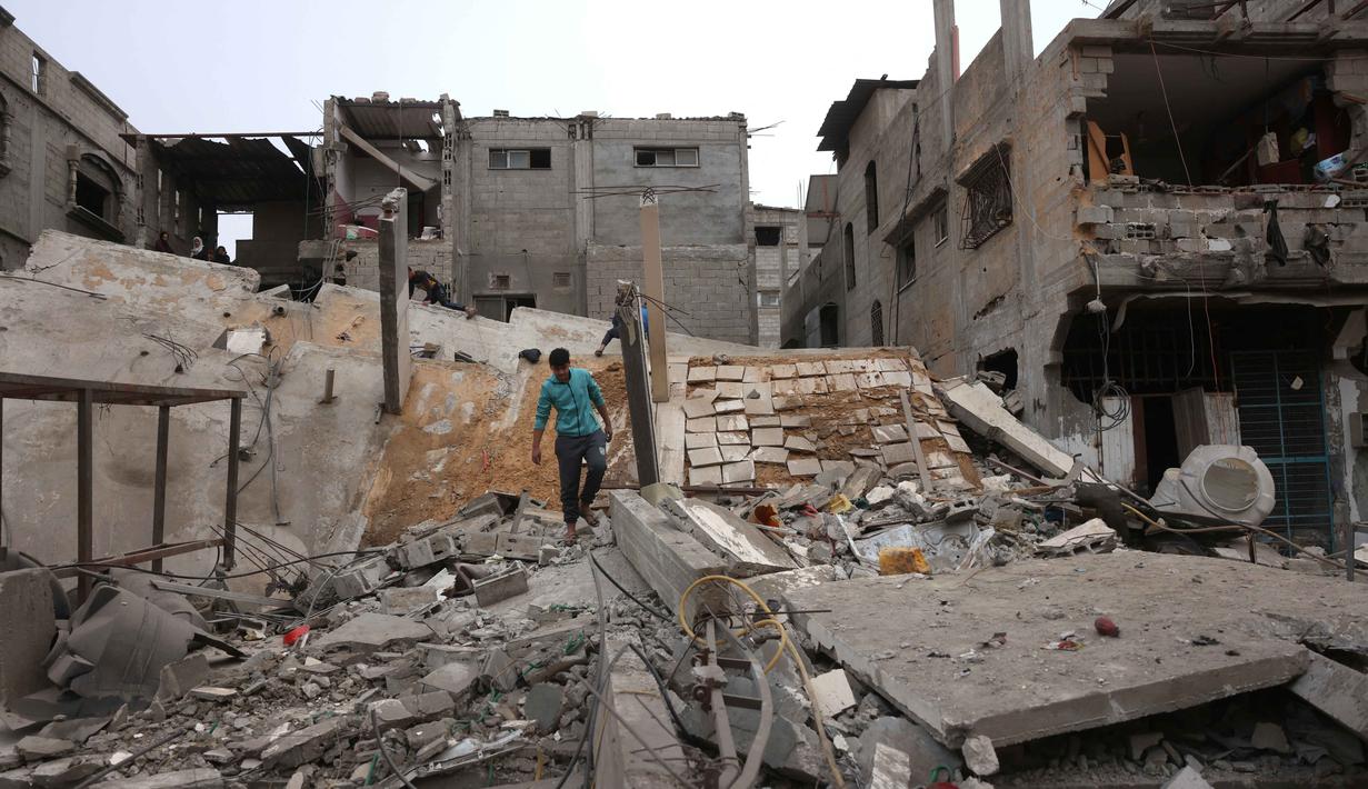 Seorang pria Palestina yang mengungsi berjalan di atas puing-puing setelah pesawat Israel menargetkan sebuah rumah berlantai lima tadi malam, di Khan Yunis, Jalur Gaza selatan pada Kamis 6 Februari 2026. Ketegangan di Jalur Gaza kembali memanas. (Bashar Taleb/AFP)