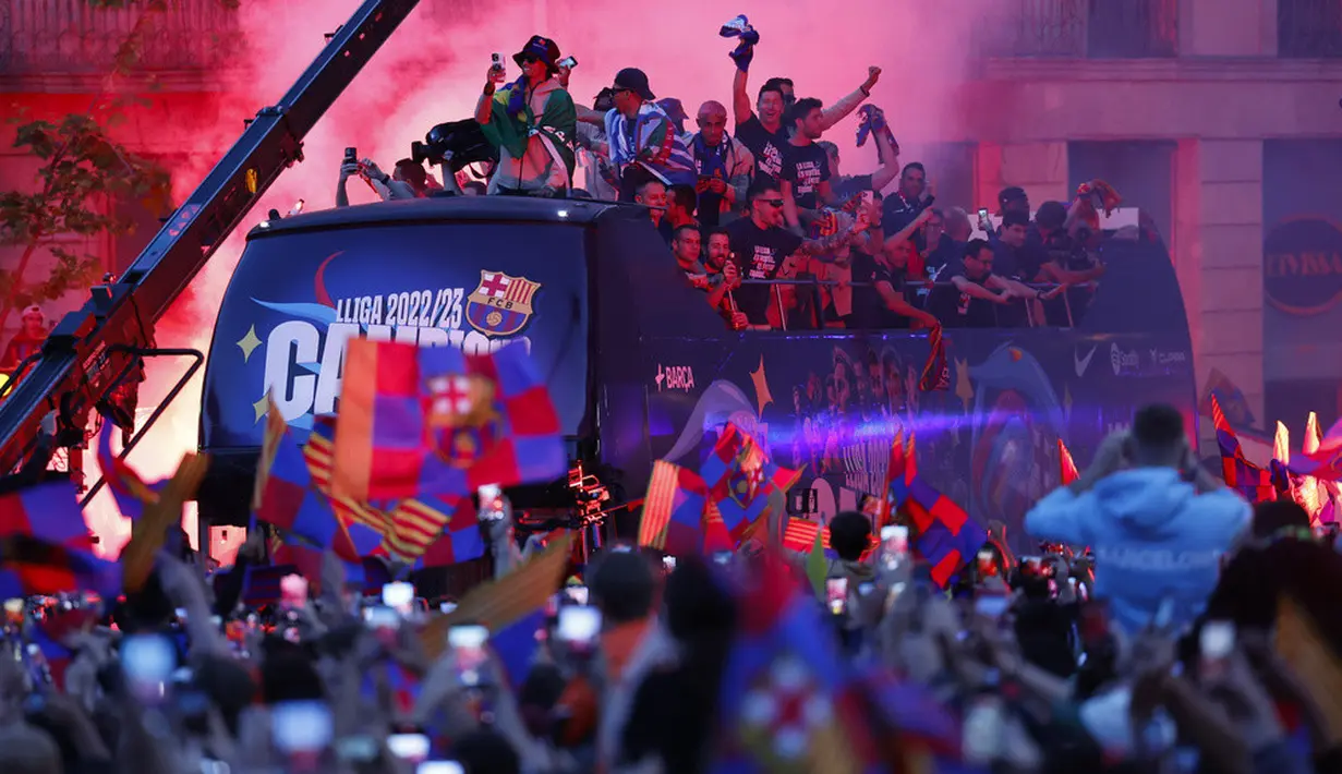 <p>Para pemain Barcelona melakukan selebrasi di atas bus saat parade perayaan kemenangan Liga Spanyol di Barcelona, Spanyol, Senin (15/5/2023). (AP Photo/Joan Monfort)</p>