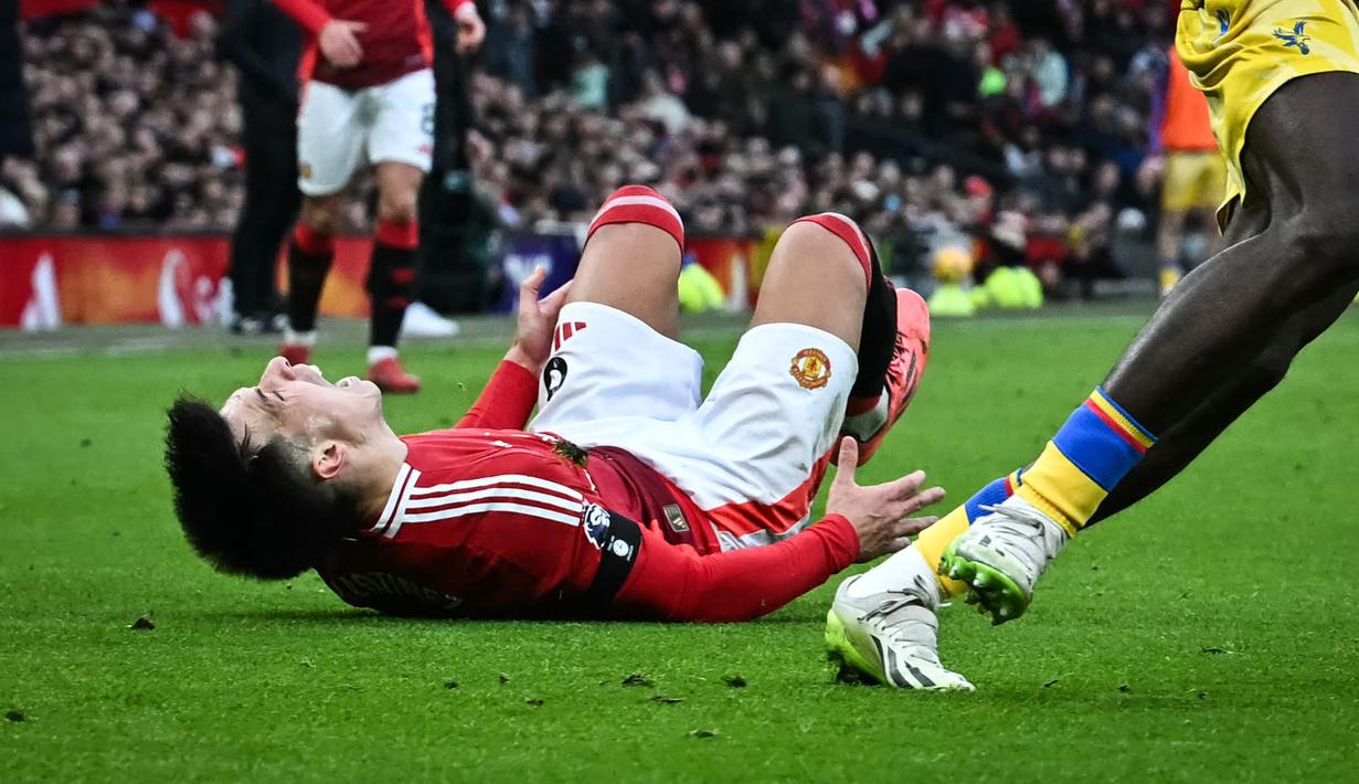 Pemain Manchester United, Lisandro Martinez mengeram kesakitan dalam laga lanjutan Liga Inggris 2024/2025 melawan Crystal Palace di Old Trafford, Manchester, Inggris, Minggu (02/02/2025). (AFP/Paul Ellis)