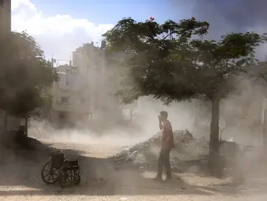 Seorang pria Palestina berdiri di samping kursi roda kosong setelah ledakan di kawasan Saftawi, barat Jabalia di Jalur Gaza utara pada 25 Agustus 2025, di tengah perang yang sedang berlangsung antara Israel dan kelompok militan Palestina Hamas. (BASHAR TALEB/AFP)