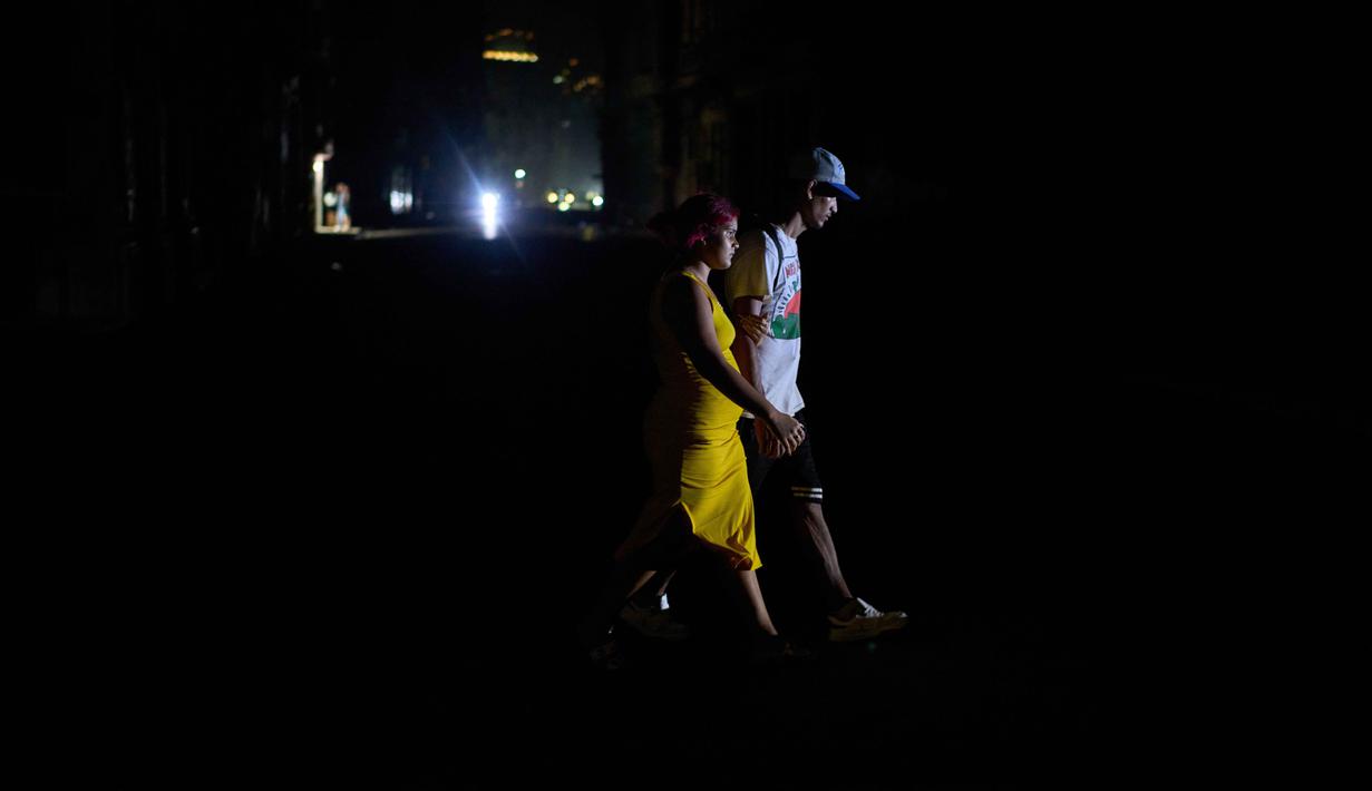 Orang-orang menyeberang jalan saat pemadaman listrik di Havana, Kuba, Rabu 4 Maret 2026. Pemadaman listrik besar melanda dua pertiga wilayah Kuba, termasuk ibu kota Havana. (AP Photo/Ramon Espinosa)