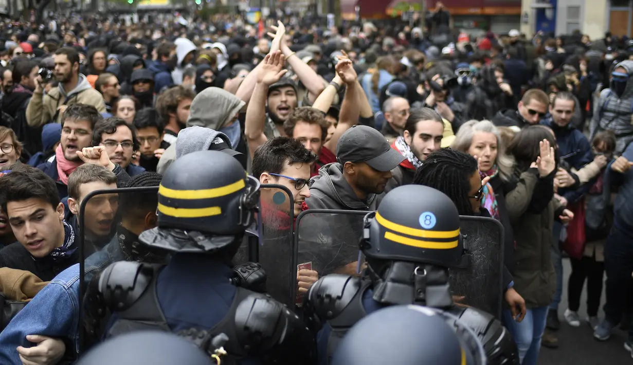 Polisi anti huru-hara terlibat saling dorong dengan pengunjuk rasa sehari setelah pemilihan presiden Prancis, Senin (8/5). Mereka menduga suara mereka tidak masuk ke dalam kotak suara yang memenangkan Emmanuel Macron. (AFP Photo/ Lionel BONAVENTURE)