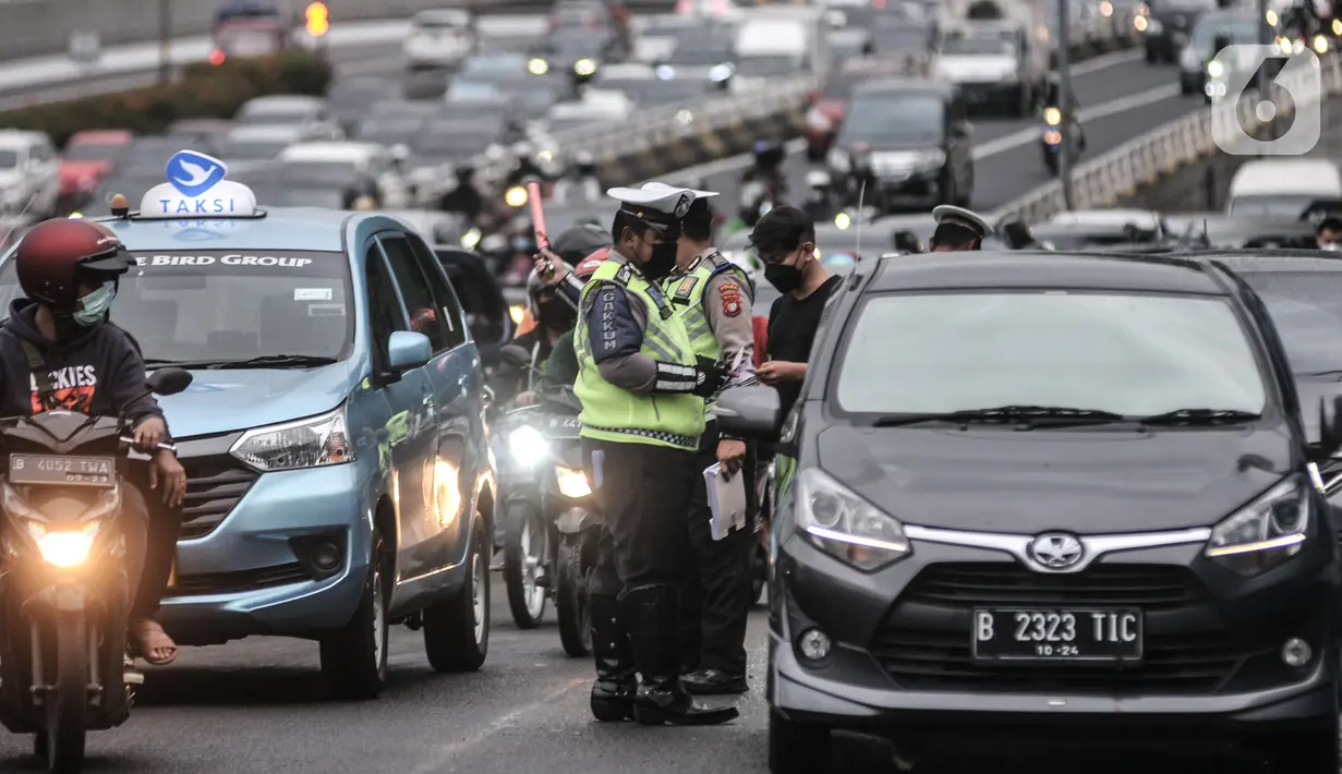 Petugas kepolisian menilang pengendara mobil yang melanggar aturan ganjil genap di Jalan MT Haryono, Jakarta, Kamis (28/10/2021). Direktorat Lalu Lintas Polda Metro Jaya mulai hari ini memberlakukan sanksi tilang kepada pelanggar ganjil genap di 13 ruas jalan DKI Jakarta. (merdeka.com/Iqbal S Nugroh