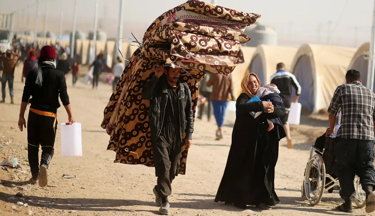 Seorang pria bersama keluarganya membawa kasur menuju kamp pengungsian Khazer, Irak(28/11). Mereka meningglkan daerah yang menjadi kawasan perang antara Pasukan Irak dan ISIS ke tempat yang lebih aman. (Reuters/Mohammed Salem)