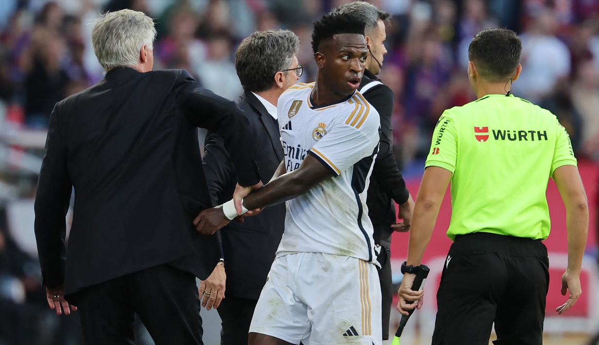 Beruntung, Vinicius tidak diganjar kartu apa pun karena aksinya yang terkesan mengulur waktu tersebut. Pada akhirnya, Real Madrid mengunci kemenangan 2-1 atas Barcelona. (AFP/Lluis Gene)