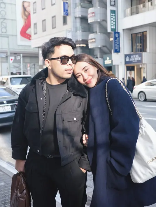 Bersandar di bahu sang suami, Aaliyah Massaid kenakan long coat navy dan tas Chanel 22 putih. Thariq Halilintar tampil cool dengan t-shirt, celana panjang, dan jaket tebal [@aaliyah.massaid]