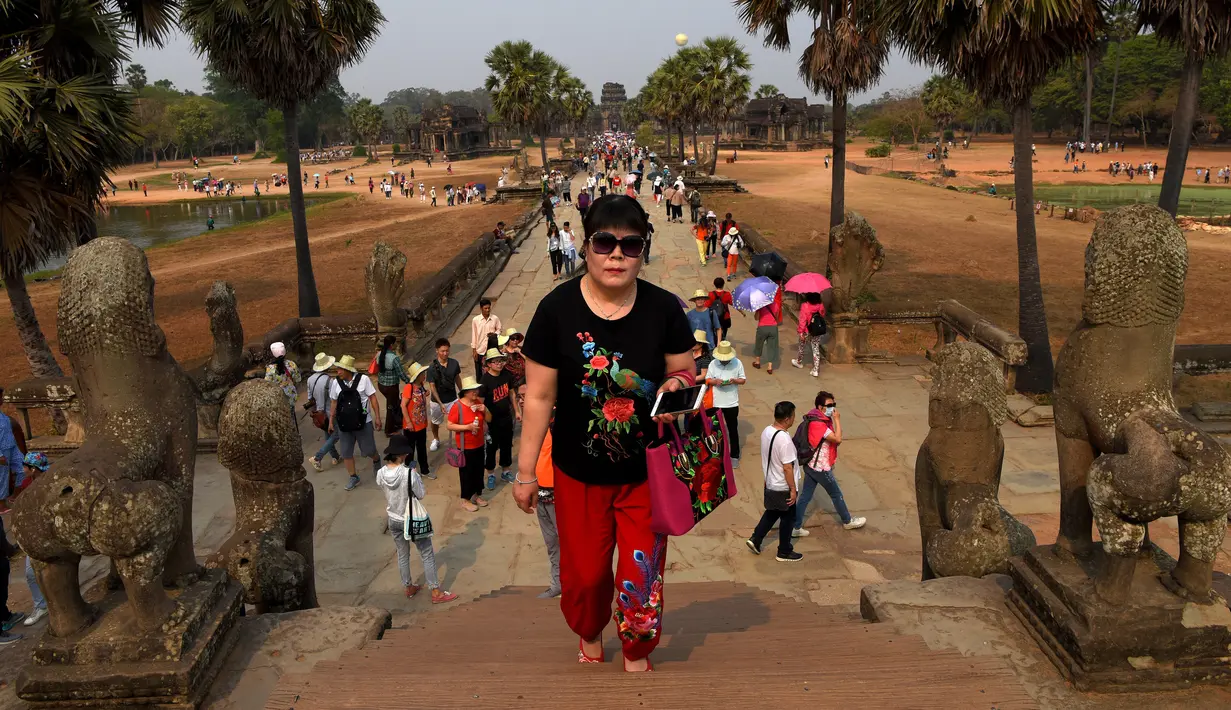 Turis mengunjungi candi Angkor Wat di provinsi Siem Reap, barat laut Kamboja pada 16 Maret 2019. Candi Hindu ini terletak di dataran Agkor, Kamboja, yang juga dipenuhi candi-candi indah lainnya. (TANG CHHIN Sothy / AFP)