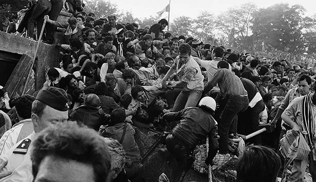 Para suporter coba menyelamatkan diri dari tembok ambruk di Stadion Heysel, Brussels Belgiapada tanggal 29 Mei 1985 saat laga final Liverpool vs Juventus. . (AP Photo/Gianni Foggia, File)