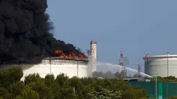 Pemadam kebakaran berusaha memadamkan api di kilang minyak milik perusahan Amerika di Etang de Berre, Marseille, Perancis, (14/7/2015). Pihak berwenang sudah menerapkan langkah khusus untuk mencegah pencemaran hidrokarbon. (REUTERS/Philippe Laurenson)