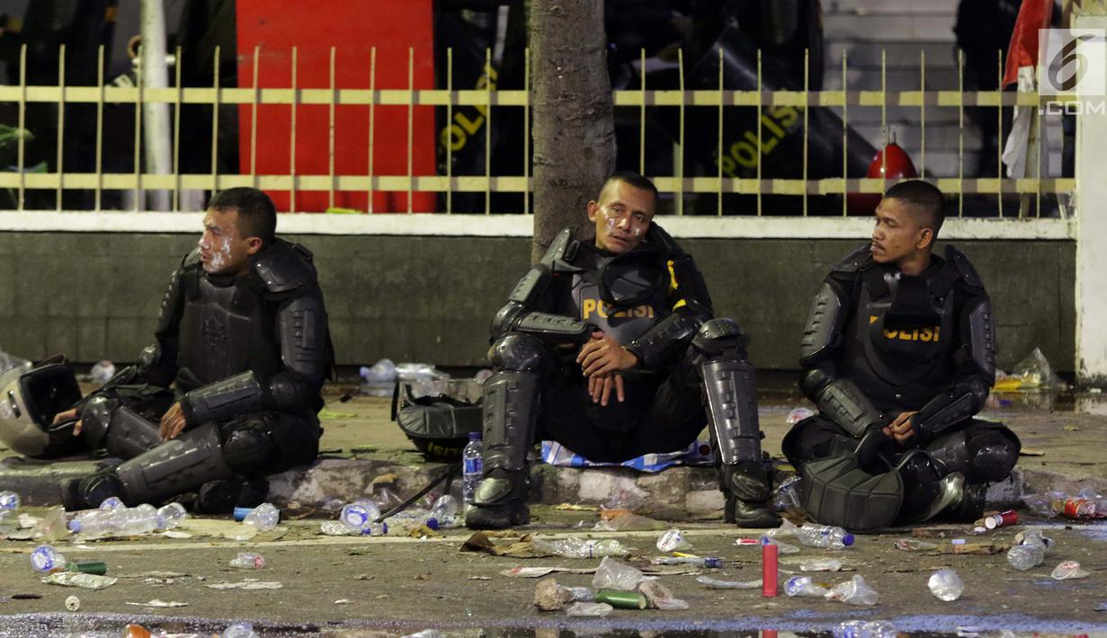 Personil Kepolisian dari satuan Brimob beristirahat di sela-sela menghalau massa yang berlaku anarkis di sekitar depan Gedung Bawaslu, Jalan MH Thamrin, Jakarta, Rabu (22/5/2019). Aksi unjuk rasa yang dimotori GNKR berakhir ricuh. (Liputan6.com/HelmiFithriansyah)