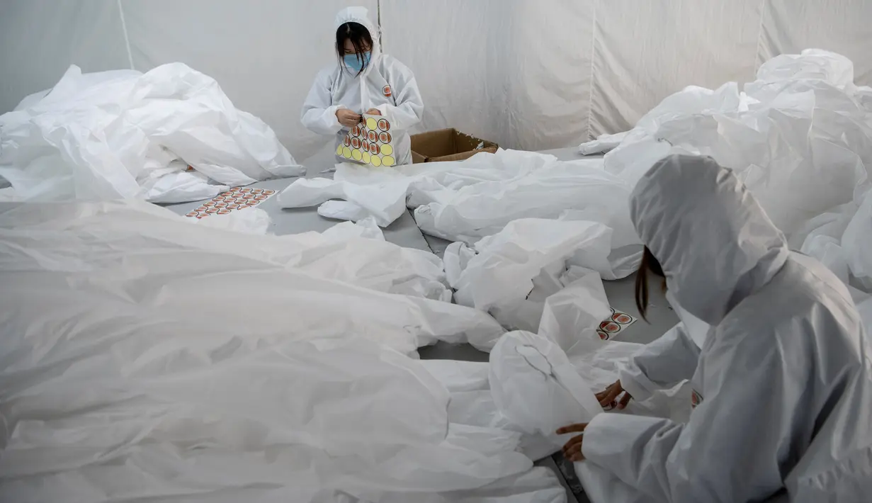 Para pekerja memeriksa pakaian antivirus yang sudah selesai di pabrik garmen Zhejiang Ugly Duck Industry, di Wenzhou, 28 Februari 2020. Wabah virus corona di China membuat produsen pakaian itu mulai memproduksi baju hazmat yang banyak diburu orang untuk melindungi dirinya. (NOEL CELIS/AFP)