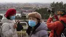 Pengunjung menikmati pemandangan menghadap Kota Terlarang dari taman Jingshan pada hari bersalju di Beijing, China, Selasa (19/1/2021). China sekarang berurusan dengan pandemi virus corona di timur lautnya yang dingin, mendorong penguncian ketat dan pembatasan perjalanan. (AP Photo/Ng Han Guan)