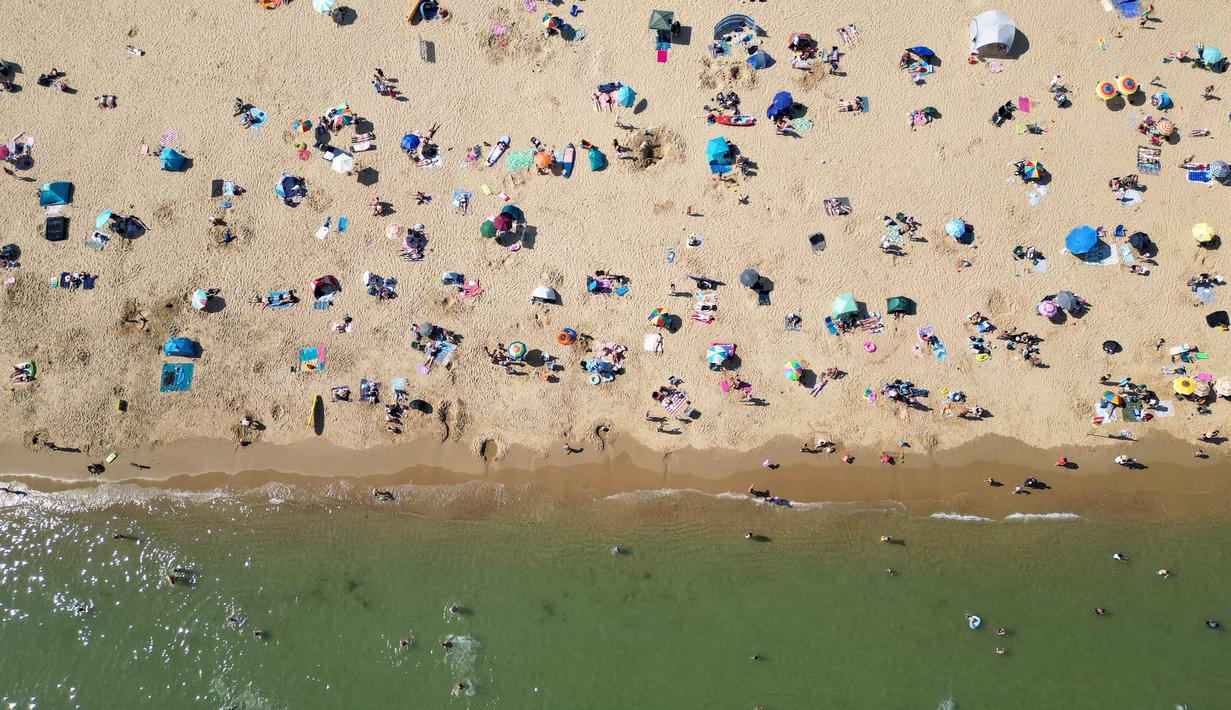 Foto udara menunjukkan orang-orang bermain dan bersantai di bawah sinar matahari di Pantai Bournemouth, Selatan Inggris pada Selasa 26 Mei 2026, saat kondisi gelombang panas menyebar ke sebagian wilayah tenggara Inggris dan London. (JUSTIN TALLIS/AFP)