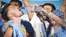 Pemain Manchester City, Jack Grealish (kiri), menikmati minuman beralkohol yang diberikan rekan satu timnya, Kalvin Phillips (kanan) dalam perayaan Trebele Winners di kota Manchester, Selasa (13/6/2023) dini hari WIB. (AFP/Oli Scarff)